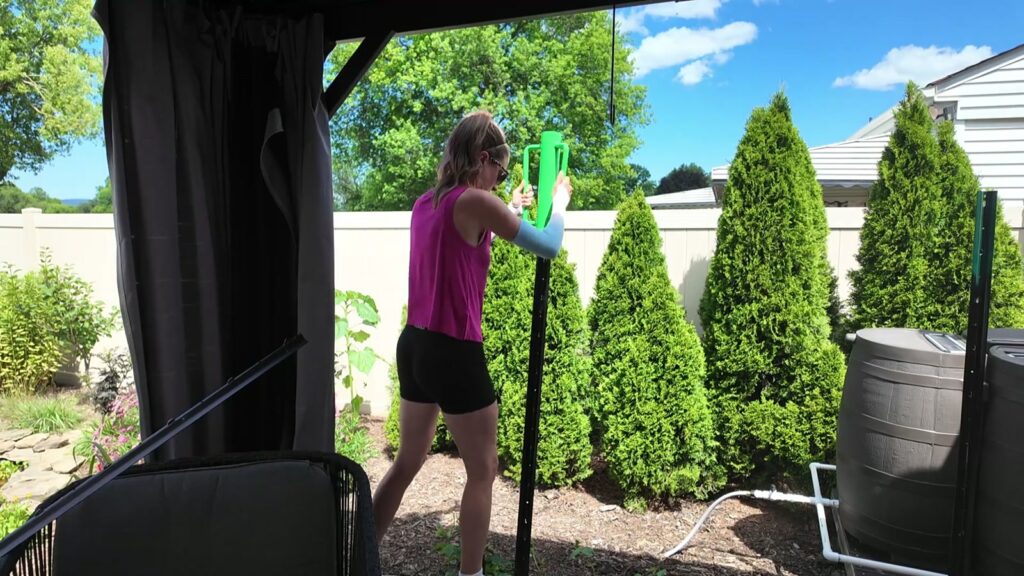 Woman driving a metal fence post into a mulched bed